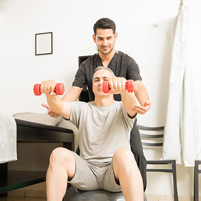 Physical Therapist guiding a patient's elbows while they use small hand weights